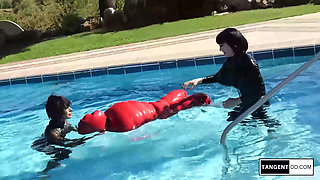 TANGENTOD Women in Black Catsuits Float Red Latex Encased Figure on Inflatable Rubber Pool Toy