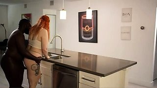 Curvy redhead having fun with a black bull in the kitchen